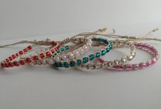 five bracelets with different colored beads and string wrapped around them on a white surface