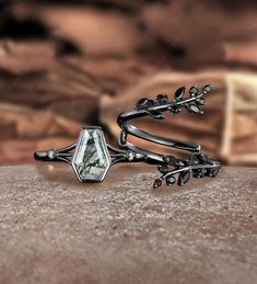 a close up of a ring on top of a stone surface with flowers and leaves