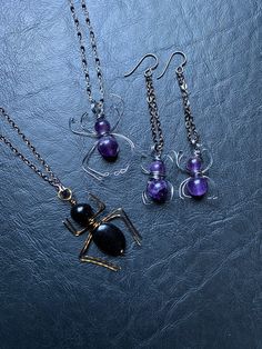 "Creepy crawly friends just in time for spooky season! Whether you love spiders or abhor them, these will add a little bit of whimsy to your day. Genuine polished amethyst spheres wrapped in gunmetal wire to create these little crawlies! Necklace is paired with a beautifully wirewrapped gemstone necklace, using tiny faceted black spinel wrapped in silver wire, closing with a sterling silver lobster claw clasp. This necklace sparkles like a silky starry spider web. Earrings are suspended from hyp Mystical Handmade Jewelry For Halloween, Handmade Mystical Jewelry For Halloween, Purple Halloween Jewelry Gift, Handmade Spooky Dangle Jewelry, Gothic Purple Jewelry For Halloween, Gothic Purple Jewelry Gift, Spooky Jewelry With Ear Wire For Gift, Purple Metal Jewelry For Halloween, Mystical Nickel-free Halloween Jewelry