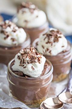 small desserts with whipped cream and chocolate shavings in glass jars on a table