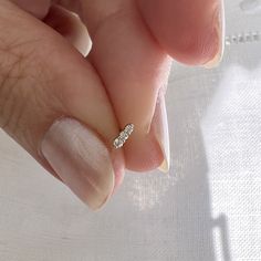 a woman's hand with a diamond ring on her finger and white nail polish