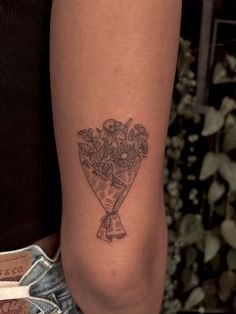 a woman with a tattoo on her leg holding a bouquet of flowers