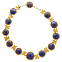 Lapis Necklace in 14k & 18K Gold. This Riviera styled necklace features 12 cabochon-cut lapis gemstones, each measuring 19–16 mm, and exhibits gold detailing within each stone, enhancing the royal blue hue. The necklace is crafted from 14K & 18K yellow gold, and surround each lapis stone with a textured design. The gold is also crafted into paisley art nouvea design between each stone, adding a feel of historical elegance to the piece. Comfortably sized at 17 inches and weighing 71.02 grams, this substantial chain necklace is a perfect gift to add to your jewelry collection. Item Details: - Type: Necklace - Metal: 14K Yellow Gold, 18K Yellow Gold - Weight: 71.02 grams - Setting: Bezel - Size: 17 inches _______________________ Stone Details: - Lapis: 12 Cabochon cut Lapis, 19-16mm (each) __ Motifs Art Nouveau, Lapis Stone, Lapis Necklace, Paisley Art, Textured Design, Metal Necklaces, Gold Details, Metallica, Art Nouveau