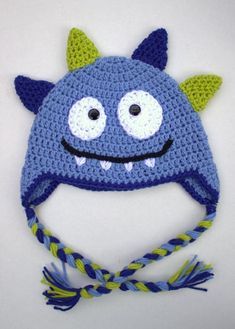 a crocheted blue hat with green horns and eyes