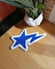 a blue and white star shaped rug sitting on top of a wooden table next to a potted plant