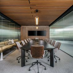 an empty conference room with chairs and a large table in front of a flat screen tv