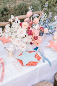 the table is set with pink and blue flowers