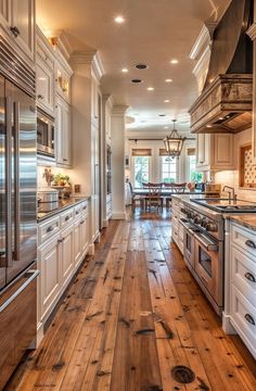 a large kitchen with white cabinets and wood flooring, along with stainless steel appliances