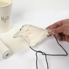 someone is making something out of fabric on the table next to a coffee cup and mug