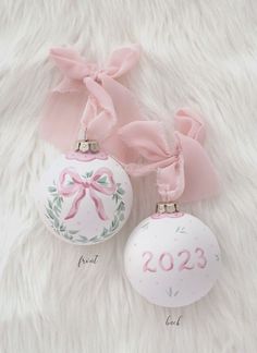 two ornaments with pink bows on them