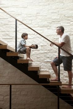 a man and boy are sitting on the stairs next to each other, looking at each other