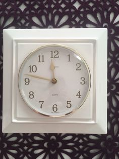 a white clock with gold hands on a wall