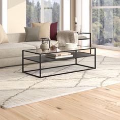 a living room scene with focus on the couch and coffee table in front of large windows