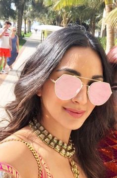 a woman wearing pink sunglasses standing on the sidewalk