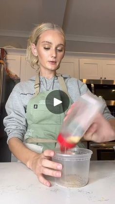 a woman in an apron mixing food into a container