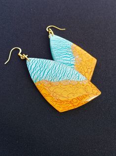 "These earrings feature the patterns of the sand and sea. On one half, pearlescent blue and white ripples move your eye back and forth and seemingly collide with an almost holographic textured golden background. They are perfect for anyone with a unique flair and anyone who cherishes the sun.  They are handmade and unique--no two have the same design. They are lightweight, which makes them a thoughtful gift for anyone who has trouble with heavier earrings. Each earring is made by hand and will have slight variations in the pattern. All of my materials are nickel-free and hypoallergenic. Reika means \"wander\" in Icelandic, and being a wanderer is crucial to my existence. As such, all of my pieces are imbued with parts of the natural world that have inspired me. It is my hope to provide thi Bohemian Gold Resin Earrings, Blue Resin Earrings For The Beach, Blue Resin Earrings For Beach, Artsy Blue Teardrop Earrings, Unique Blue Earrings For Summer, Blue Resin Teardrop Earrings, Summer Gold Resin Earrings, Unique Turquoise Earrings For Summer, Unique Blue Earrings For Beach