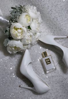 a bouquet of white flowers next to a pair of high heel shoes