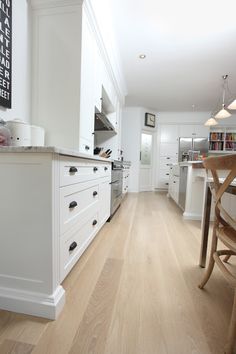 a kitchen with white cabinets and wooden floors