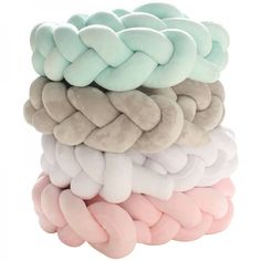 four different colored pillows stacked on top of each other in the shape of braids