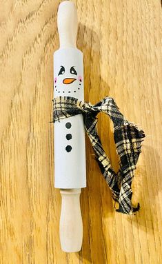 a bottle wrapped in plaid paper with a snowman head on it and a scarf around the neck