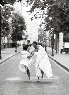 two women in white dresses are crossing the street with one woman on her back and another holding