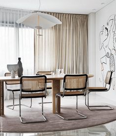 a dining room table with two chairs and a vase on top of it in front of a curtained window