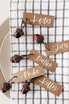 place cards with acorns and pinecones are on a plaid table cloth