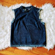 a blue jean skirt laying on top of a fluffy white rug next to a wooden floor