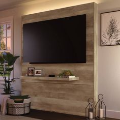 a living room with a large flat screen tv mounted on the wall next to a potted plant