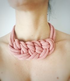 a close up of a person wearing a pink necklace with an intertwined knot on it