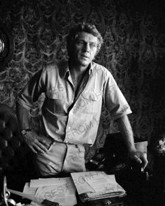 black and white photograph of man sitting at desk with papers on it's lap