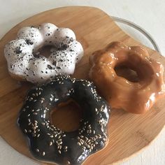 three donuts sitting on top of a wooden plate