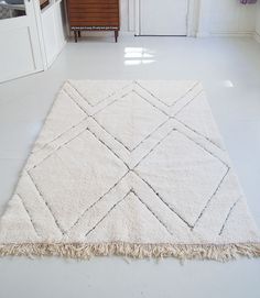 a white rug with fringes on the floor in a room that is mostly white