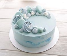 a blue cake with seashells on it is sitting on a white platter