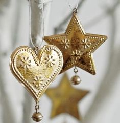 two gold heart shaped ornaments hanging from a tree