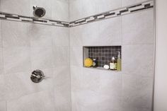 a bathroom shower with white tile and gray grout