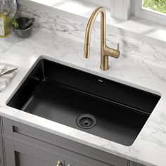 a black kitchen sink sitting under a faucet next to a white counter top