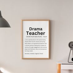 a poster hanging on the wall above a desk with a clock and lamp next to it