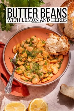 a bowl full of butter beans with lemon and herbs next to sliced bread on a table