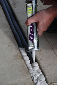 a hand holding a tube of toothpaste on top of cement