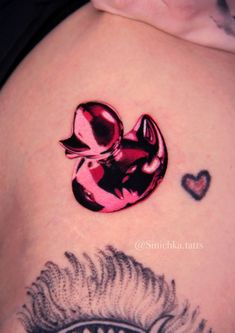 a woman's breast with a pink duck tattoo on it