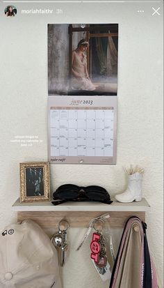 there is a hat, sunglasses and other items on the shelf in front of this calendar