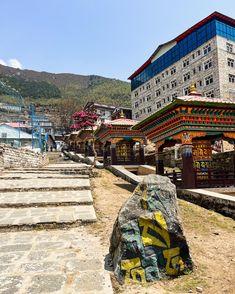 there are many steps that lead up to the building in the background, and one has a large rock on it