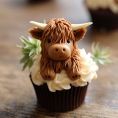 there is a cupcake decorated with a cow head on it's side and icing