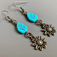 "Sunflower Earrings - Brass plated Sunflowers dangle from Turquoise Czech Glass Leaf Beads and Twisted Antiqued Brass plated Rings. Antiqued Brass Earwires Earrings measure j2.25\" from top of earwire to bottom of flowers." Turquoise Dangle Earrings With Flower Charm, Turquoise Flower-shaped Earrings With Flower Charm, Turquoise Earrings With Flower Charm As Gift, Nature-inspired Dangle Earrings With Flower Charm, Adjustable Flower-shaped Nature-inspired Earrings, Turquoise Earrings With Flower Charm, Vintage Flower Charm Dangle Earrings, Nature-inspired Drop Flower Earrings For Pierced Ears, Nature-inspired Adjustable Flower Earrings