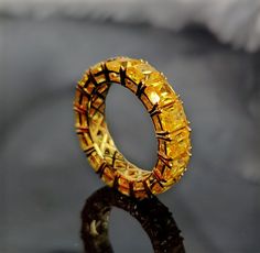 a ring made out of yellow glass sitting on top of a black surface with reflection