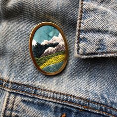 a badge with mountains on it sitting in the back pocket of someone's jeans