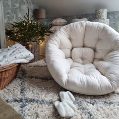 a white chair sitting on top of a rug next to a basket filled with slippers