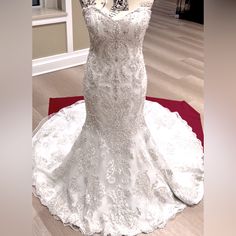 a white wedding dress on display in a room with wooden floors and red rugs