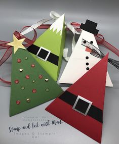 three paper christmas trees with santa hats on them and one snowman in the middle